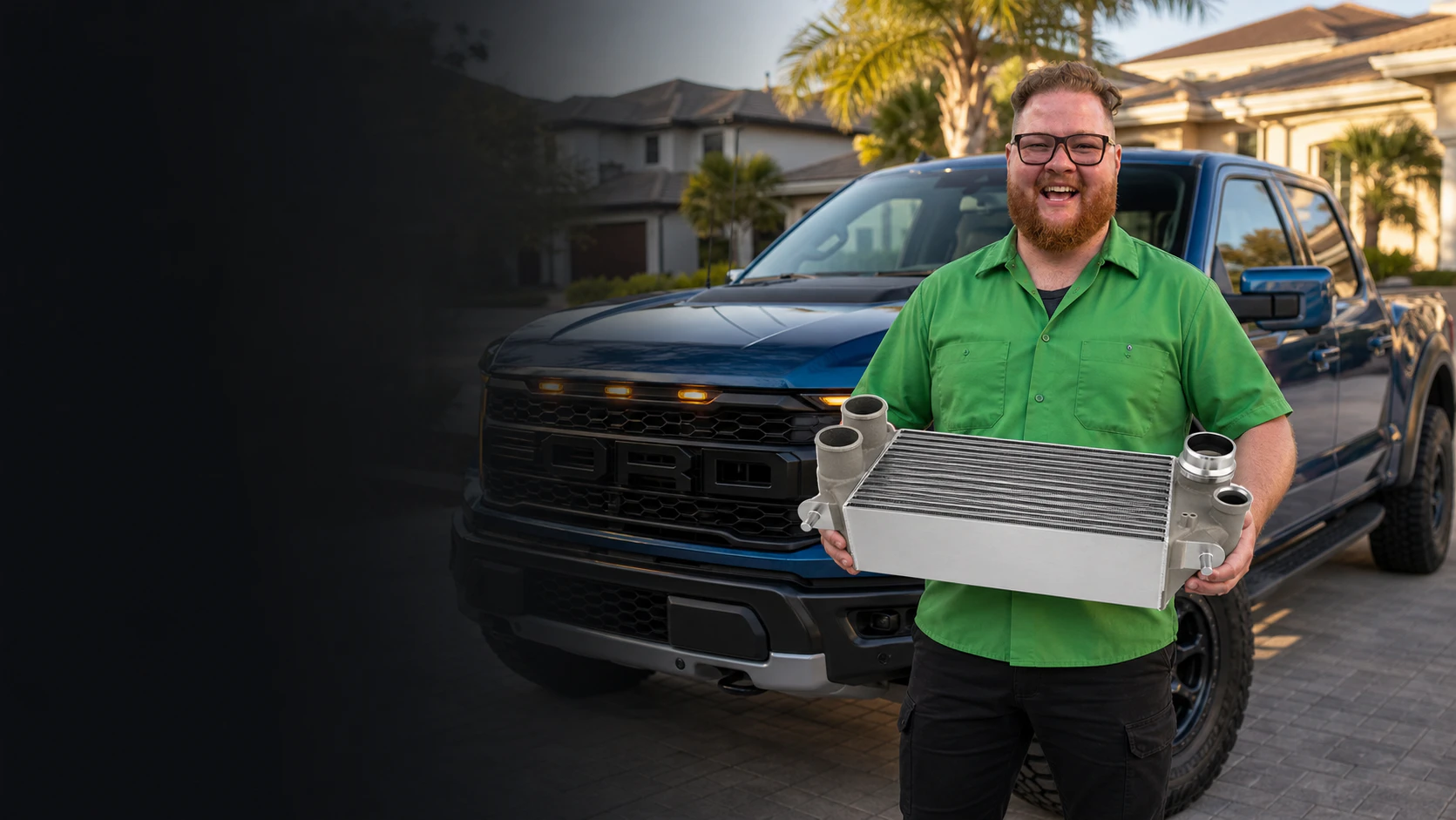 Garrett's Garage mechanic holding a performance intercooler in front of a Ford Raptor